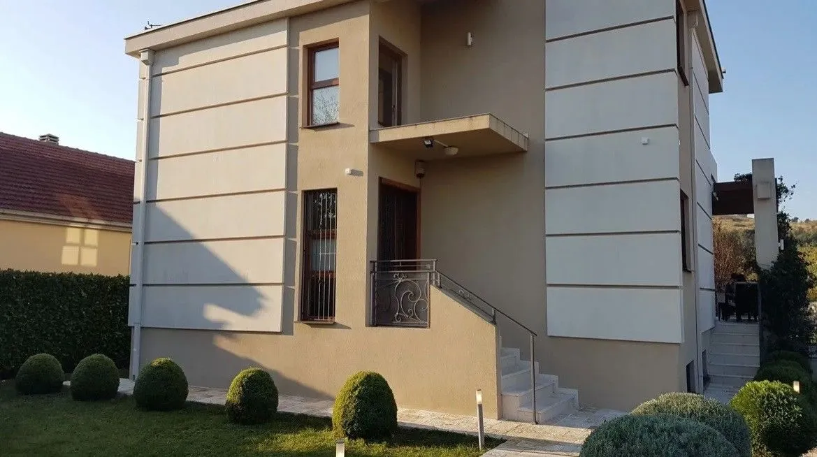 View of the exterior of the house with a landscaped yard and entrance stairs.