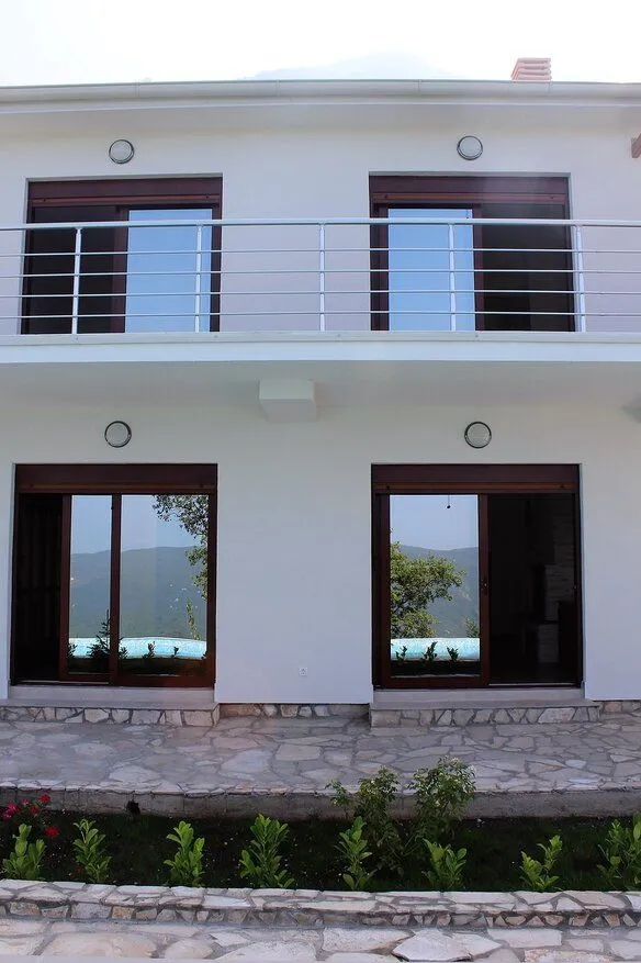 Exterior of a white house with a balcony and ground floor terrace.
