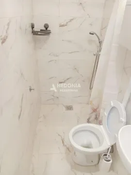 Manje kupatilo sa belim keramičkim pločicama sa teksturom mramora, tušem i WC šoljom. - image 3