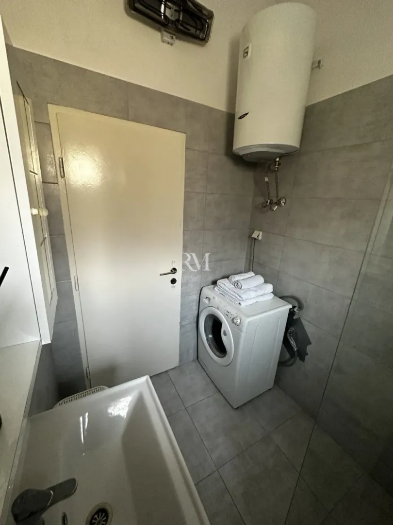 Smaller bathroom with a sink, washing machine, and water heater.