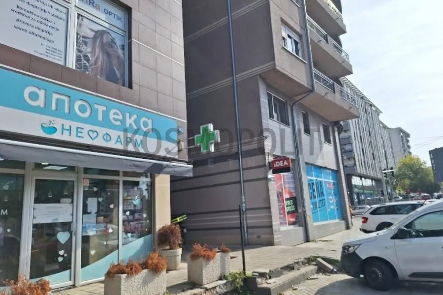 View of the building exterior with ground floor commercial spaces and sidewalk.