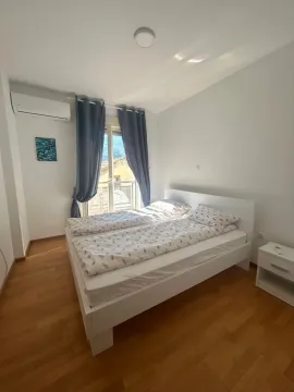 Svjetla spavaća soba sa bračnim krevetom, drvenim podom i izlazom na terasu. - image 11