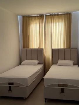 Bedroom with two single beds and a window with curtains. - image 3