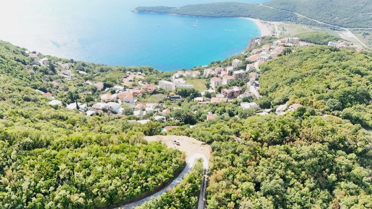 Pogled iz vazduha na obalu, more i naselje okruženo zelenilom.