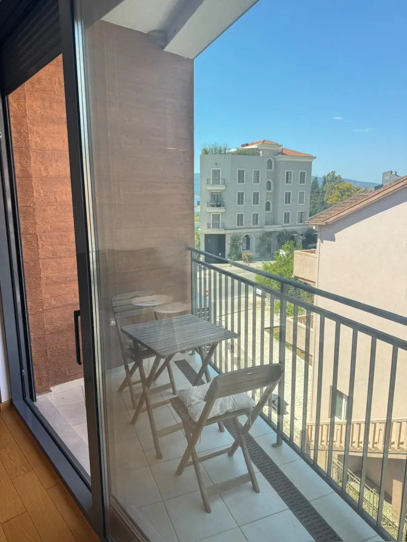 Manji namješteni balkon sa stolom i stolicama i pogledom na okolne zgrade.