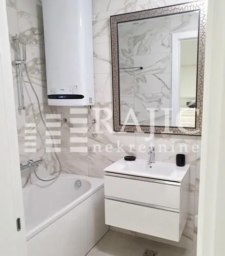 Modern bathroom with a bathtub, washbasin, and large mirror.