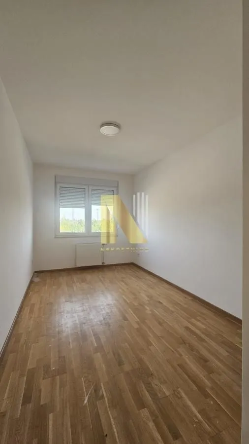 Prazna soba sa drvenim podom i prozorom.
