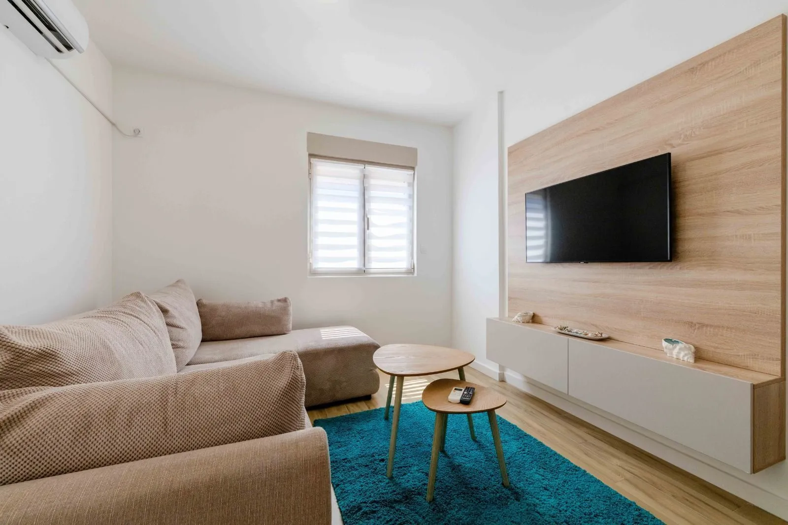 Small living room with a corner sofa, television, and wooden coffee table.