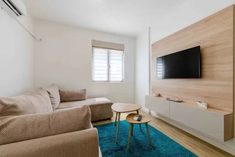 Small living room with a corner sofa, television, and wooden coffee table. - image 20