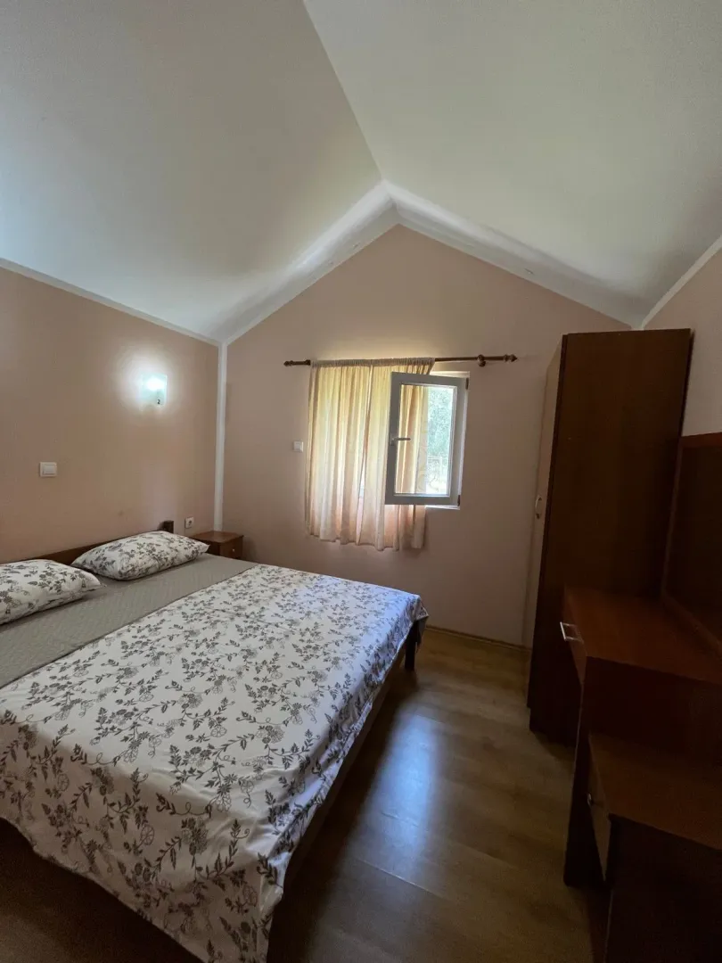 Namještena spavaća soba sa bračnim krevetom i drvenim ormarom.
