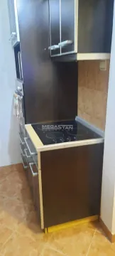 Smaller kitchen with dark cabinets and a built-in cooktop. - image 7
