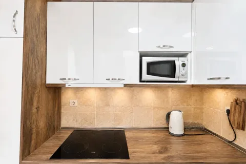 Modern kitchen with white cabinetry, built-in cooktop, and microwave. - image 4
