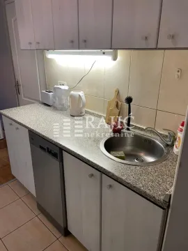 Small kitchen with a sink, countertop, and kitchen cabinets. - image 6