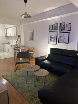 Bright living room with a black leather sofa, dining area, and kitchen in the background. - image 6