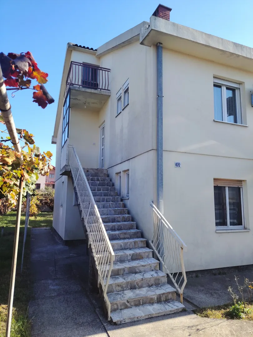 Eksterijer dvospratne kuće sa spoljnim stepeništem i balkonom.