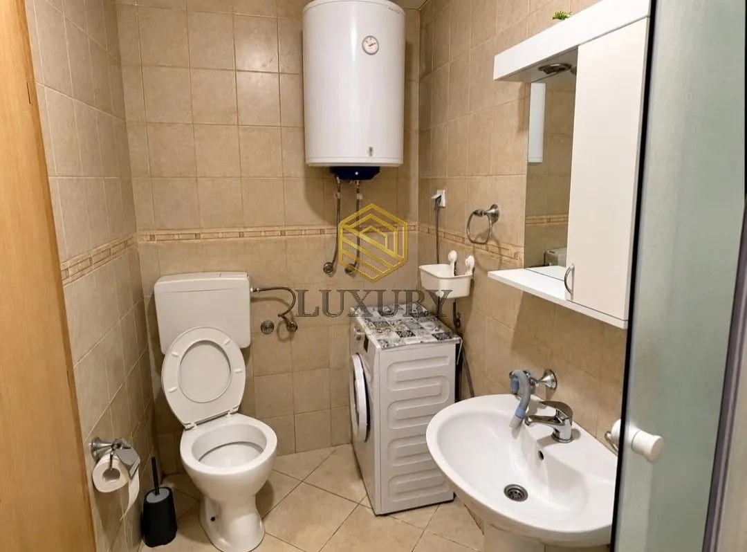 Small bathroom with toilet, washbasin, washing machine and water heater.