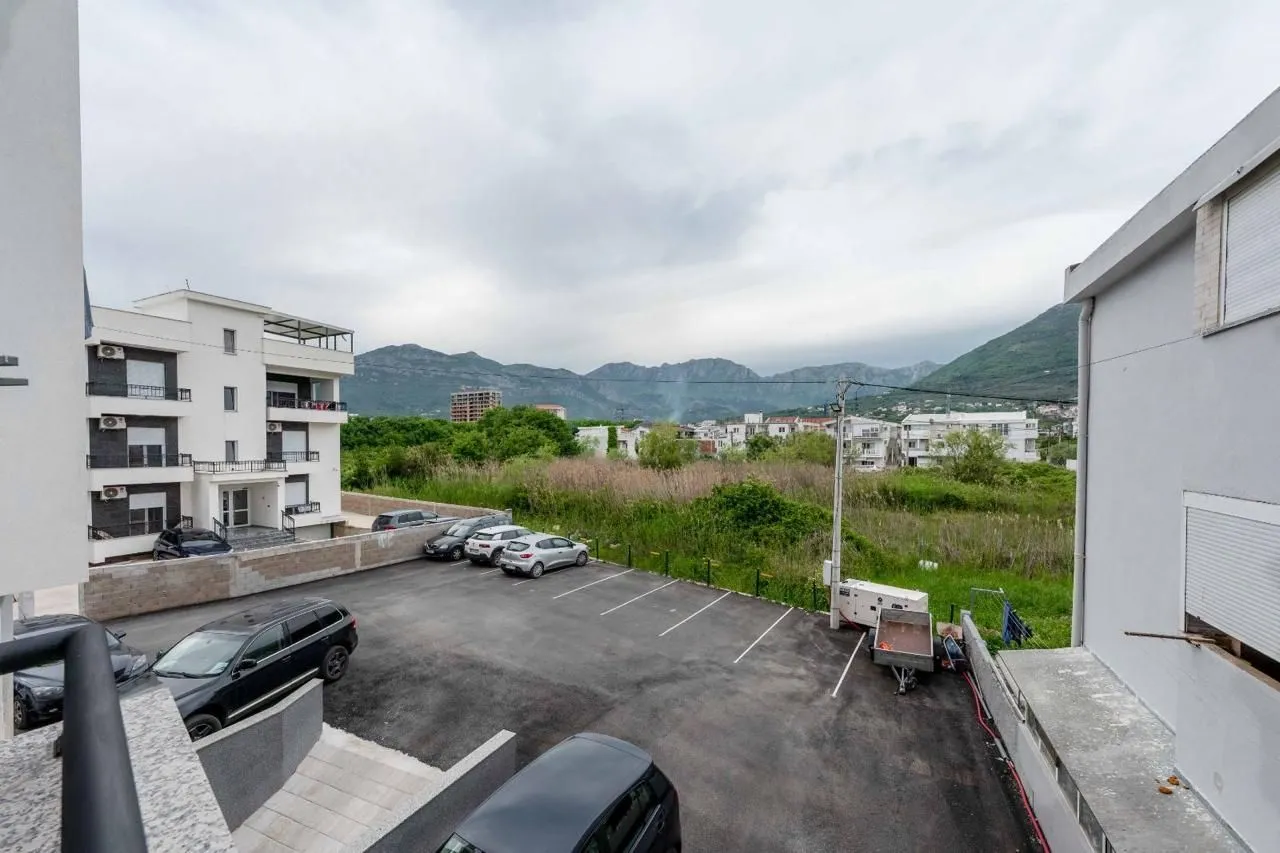 View from the terrace of the parking area in front of the building and mountains in the background.