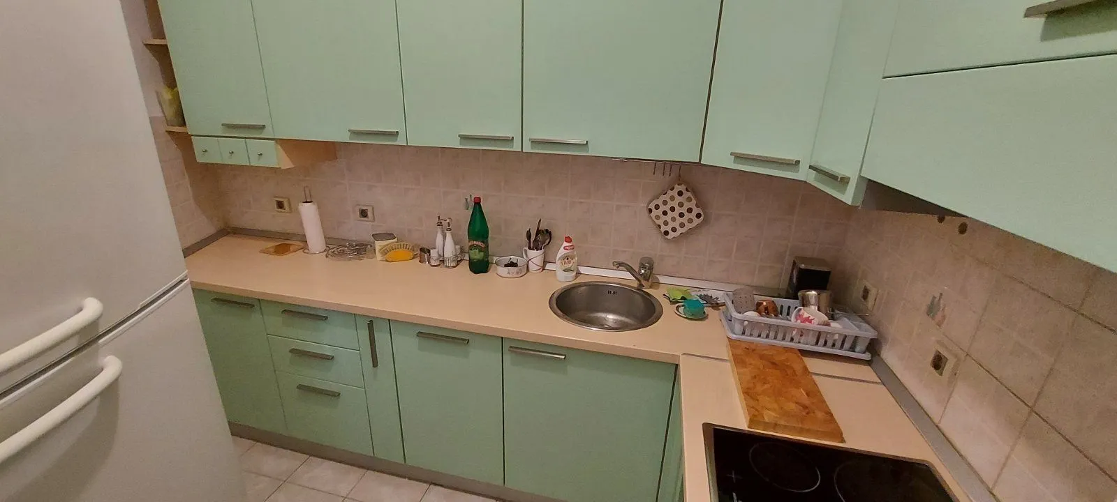 Jednostavna kuhinja sa svijetlozelenim kuhinjskim elementima.