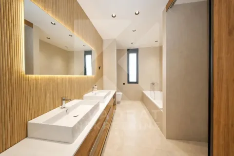 A modernly equipped bathroom with two washbasins, a large mirror, and a bathtub. - image 4