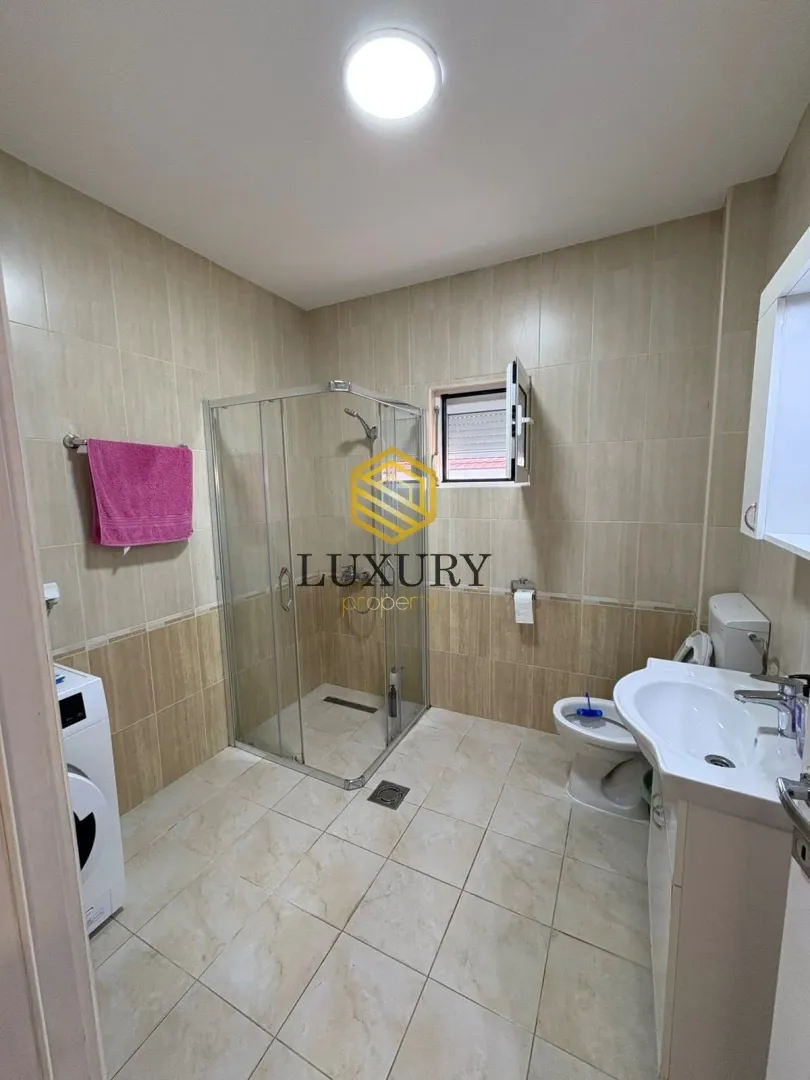 Bathroom with a shower cabin, washbasin, toilet, and washing machine.