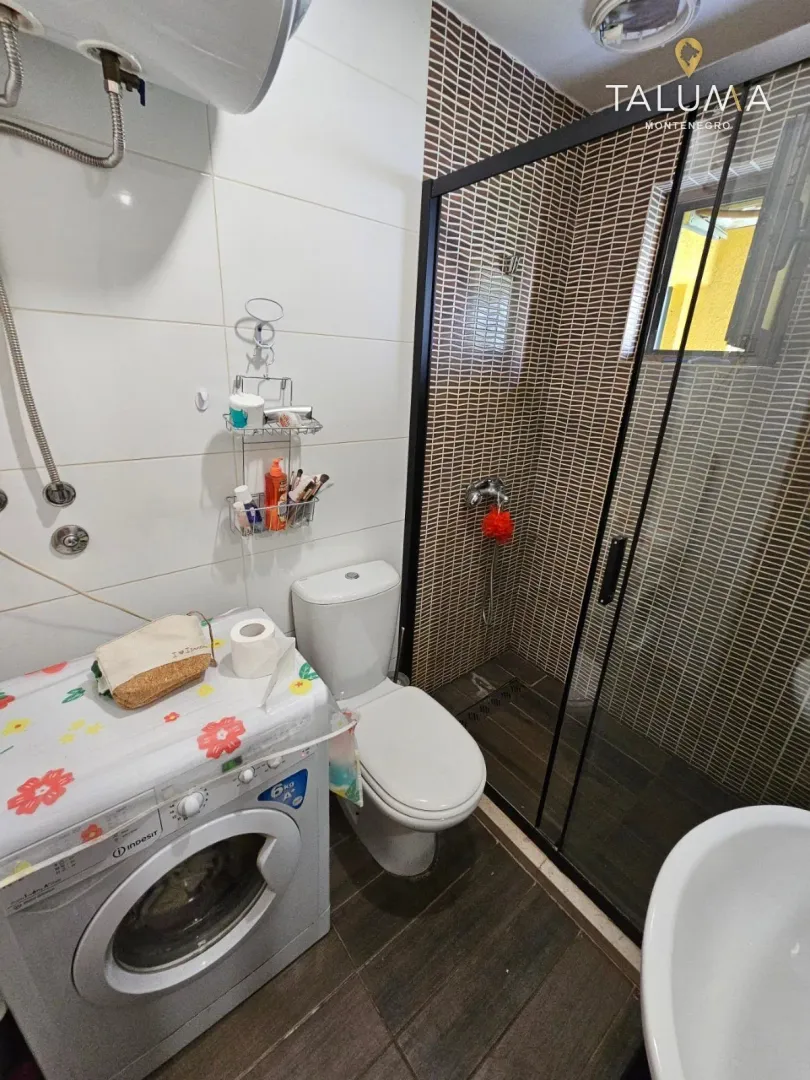 Kupatilo opremljeno tuš kabinom, WC šoljom i veš mašinom.