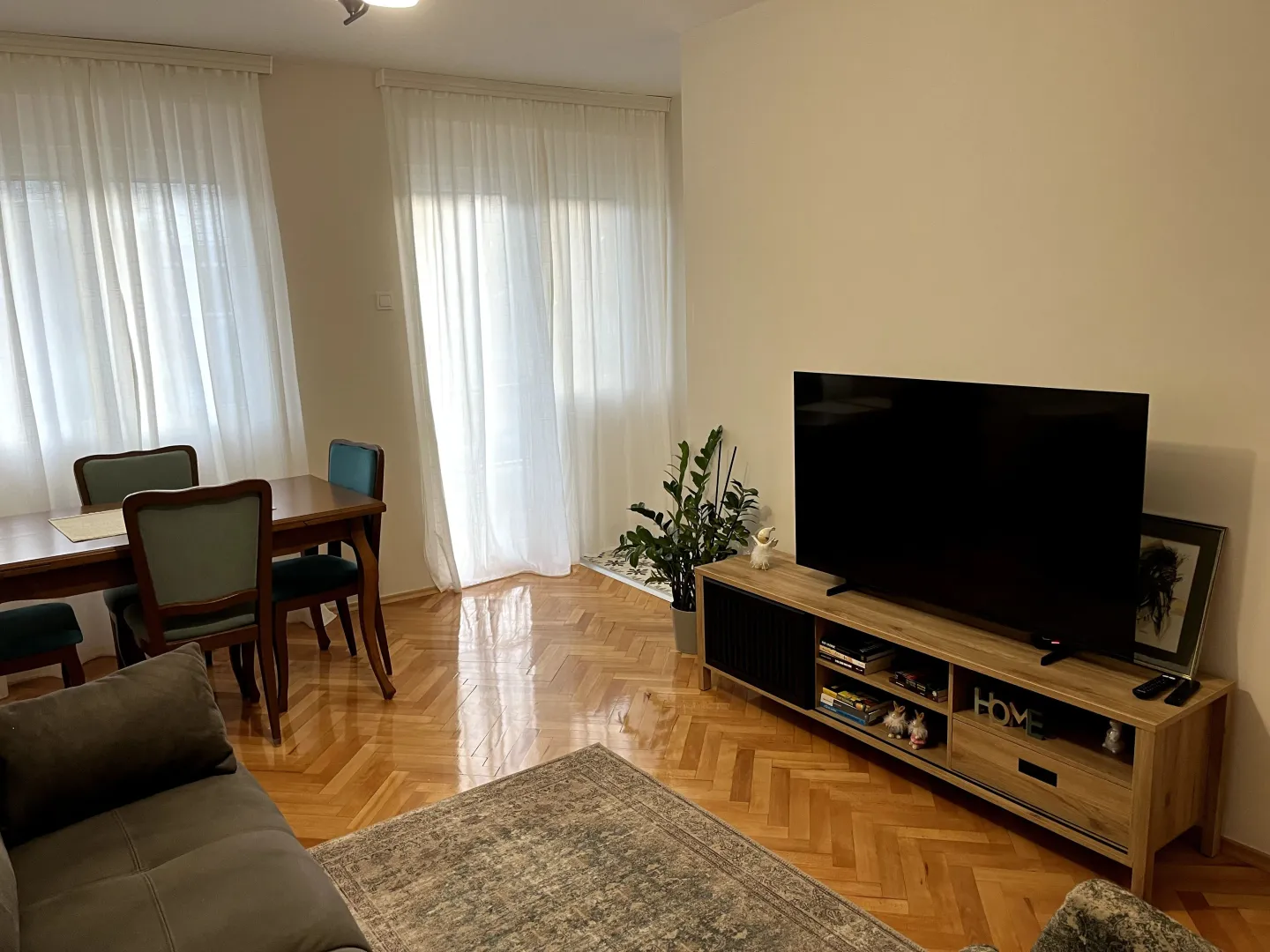 Dnevna soba sa garniturom, TV komodom i trpezarijskim dijelom.
