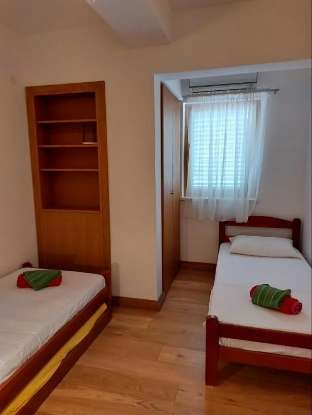 Svijetla spavaća soba sa dva singl kreveta i drvenim namještajem.
