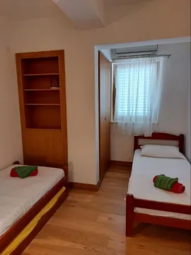 Svijetla spavaća soba sa dva singl kreveta i drvenim namještajem. - image 24