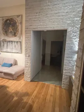 Living room with a corner sofa, decorative stone wall, and a large artwork. - image 10