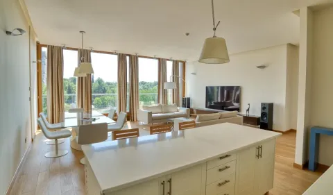 Spacious open-plan living room with a dining area and kitchen island, featuring large windows and nature views. - image 4