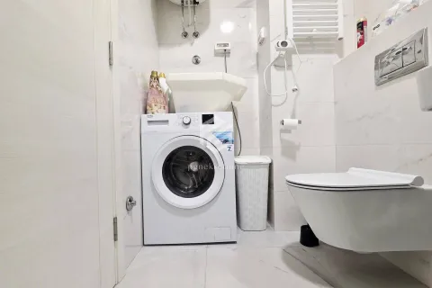Manje kupatilo sa veš mašinom, konzolnom šoljom i bijelim pločicama. - image 10