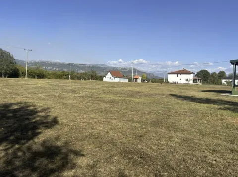 Veliko travnato dvorište sa kućama i planinskim pejzažem u pozadini. - image 8