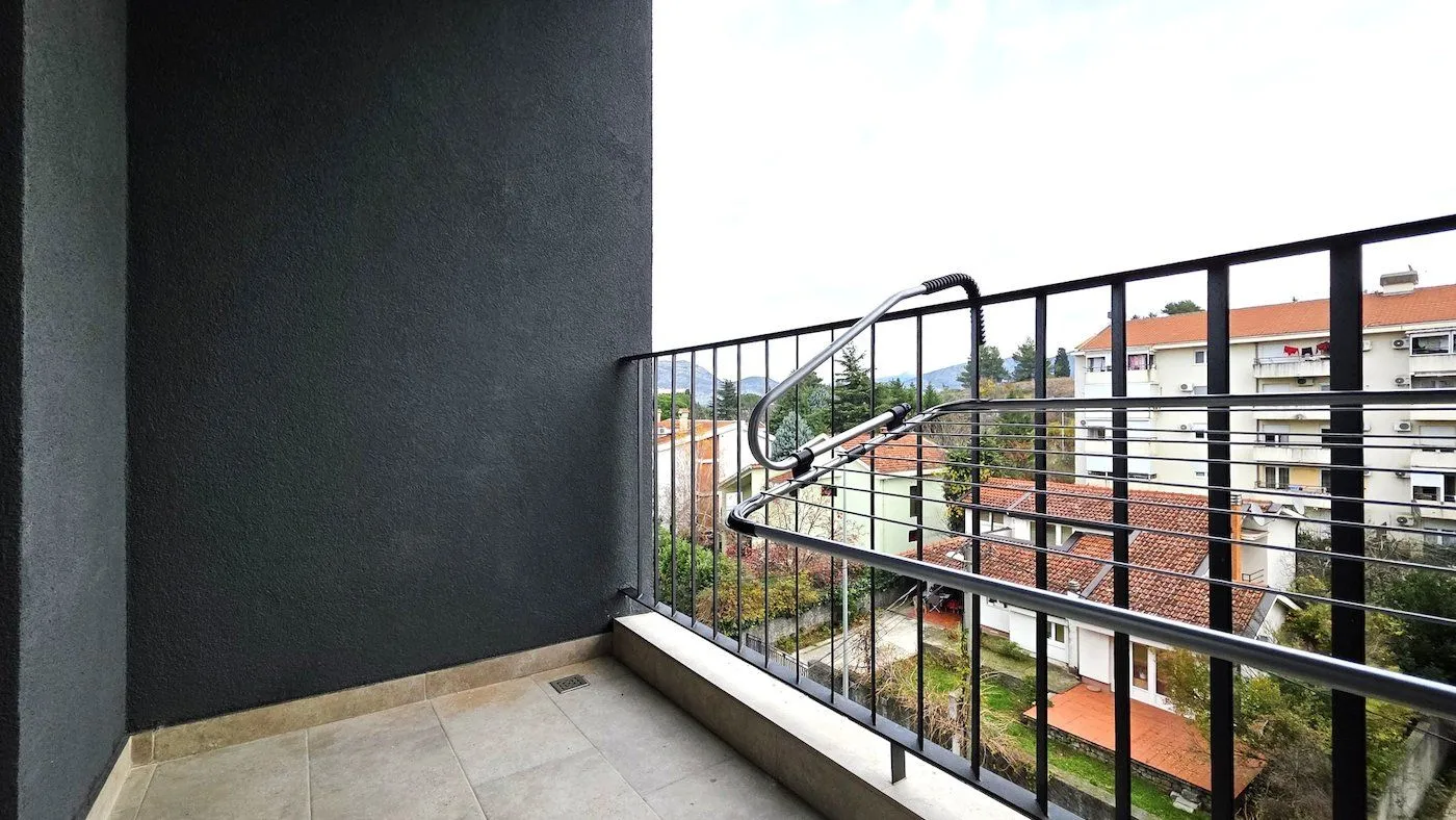 Manji popločani balkon sa ogradom i sušačem za veš.