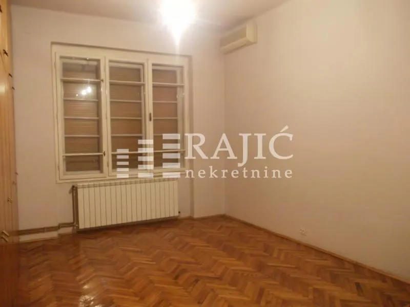 Empty room with parquet flooring and a window.