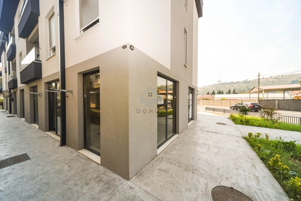 Exterior view of a modern residential building with commercial space on the ground floor.