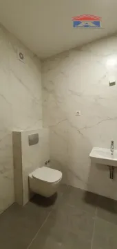 Modern bathroom with white marble tiles, wall-hung toilet, and washbasin. - image 11
