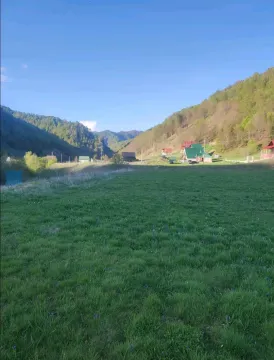 Pogled na zelenu livadu i okolne planine sa kućama u pozadini. - image 15