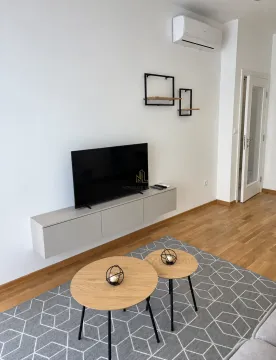 Dnevna soba sa televizorom, niskom komodom i stočićima na tepihu. - image 5
