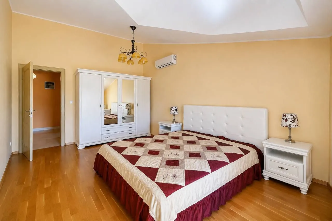 Spacious bedroom with a double bed, white wardrobe, and bedside tables.