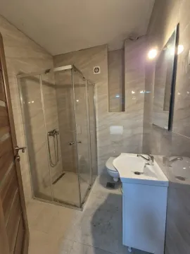 A bright bathroom featuring a glass shower cabin and a vanity sink. - image 6