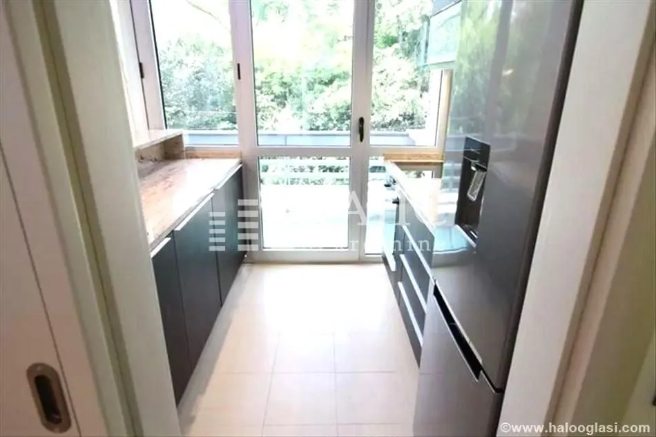 Small narrow kitchen with dark cabinets and access to the terrace.