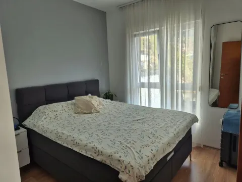 Furnished bedroom with a double bed, white nightstand, and a window with white curtains. - image 3