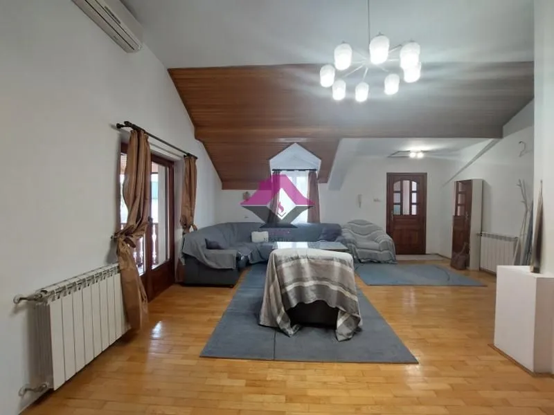 Prostrana dnevna soba sa drvenim plafonom i garniturom za sedenje.