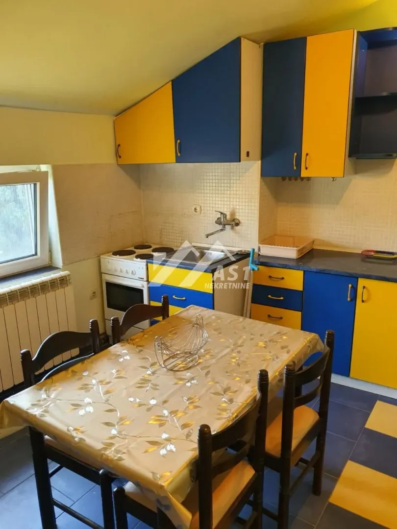 Kuhinja sa trpezarijskim stolom i plavo-žutim elementima.