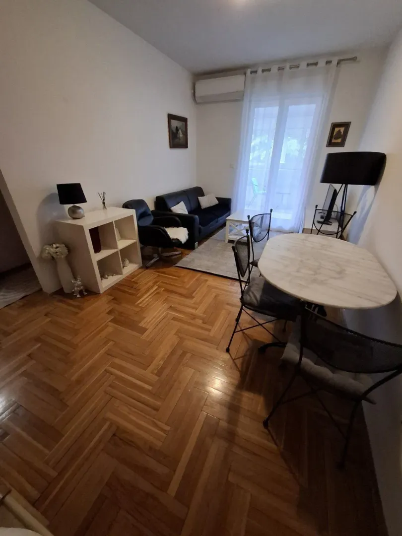 Dnevna soba sa trpezarijskim stolom, garniturom za sjedenje i parketom.