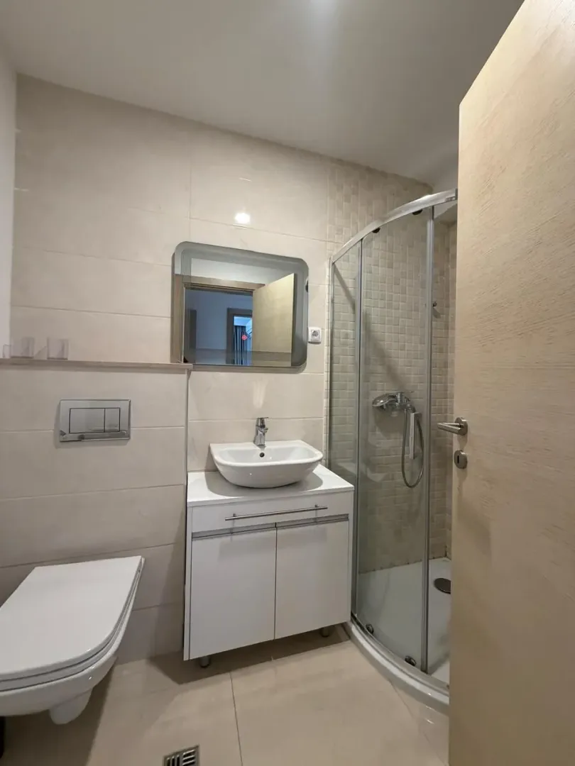 Moderno kupatilo sa tuš kabinom i bijelim sanitarijama.