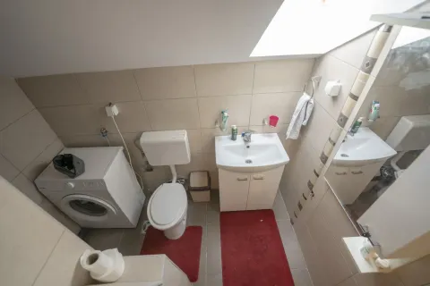 A bathroom with a washing machine and sink under a sloped ceiling. - image 7