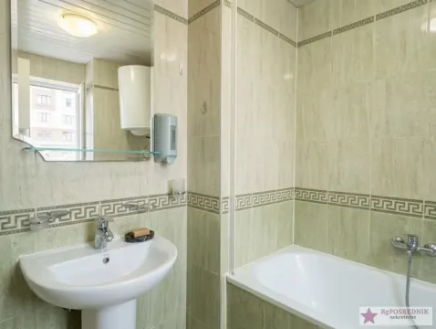 Manje kupatilo sa umivaonikom, ogledalom i kadom obloženom zelenim pločicama. - image 10