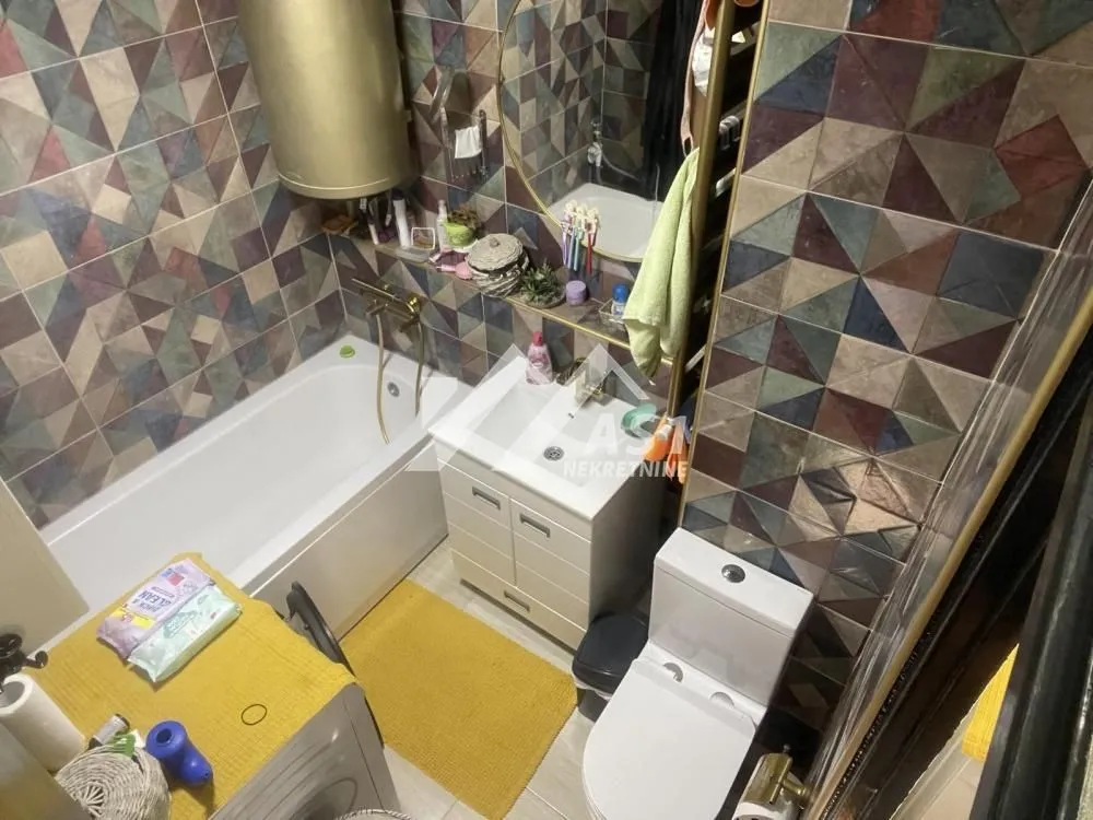 Kupatilo opremljeno kadom, umivaonikom, WC šoljom i šarenim zidnim pločicama.