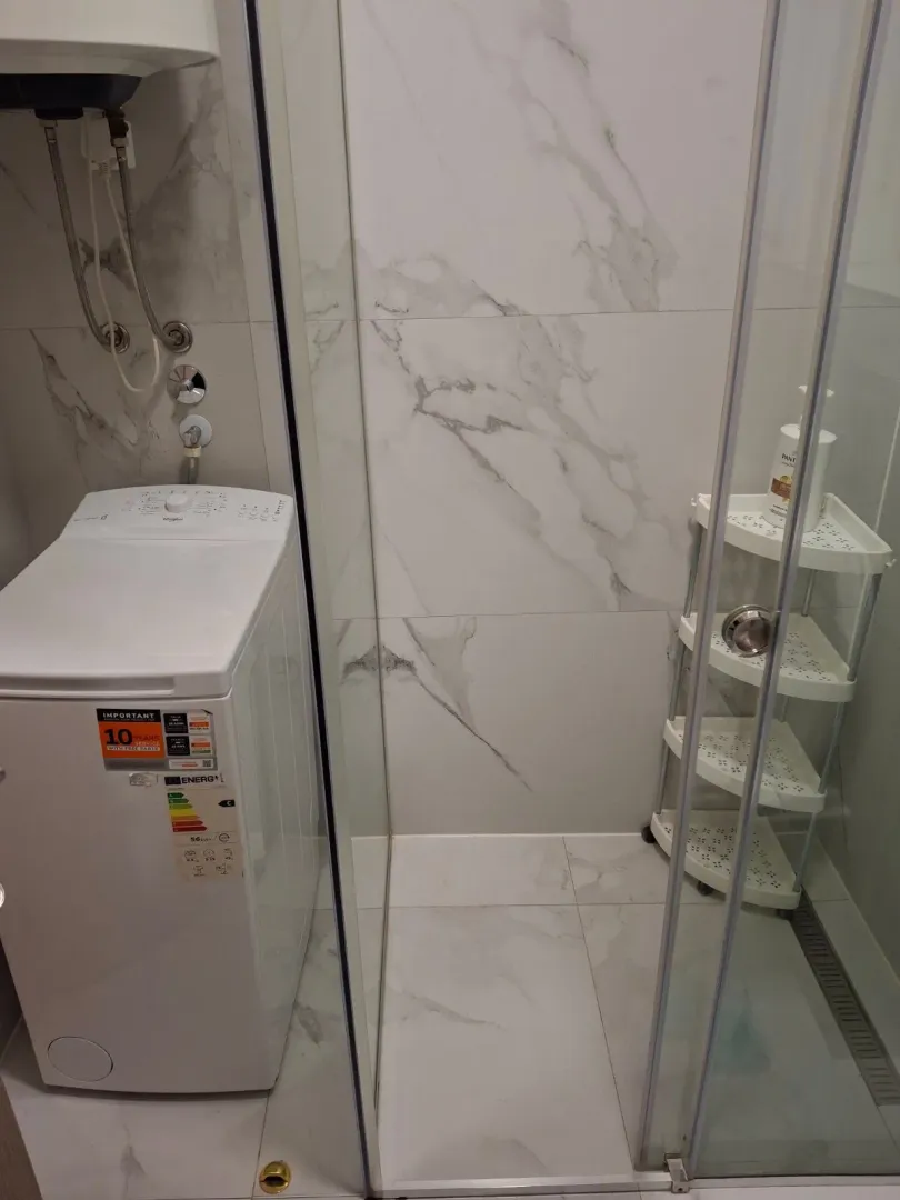 Modern bathroom with a shower cabin and washing machine.